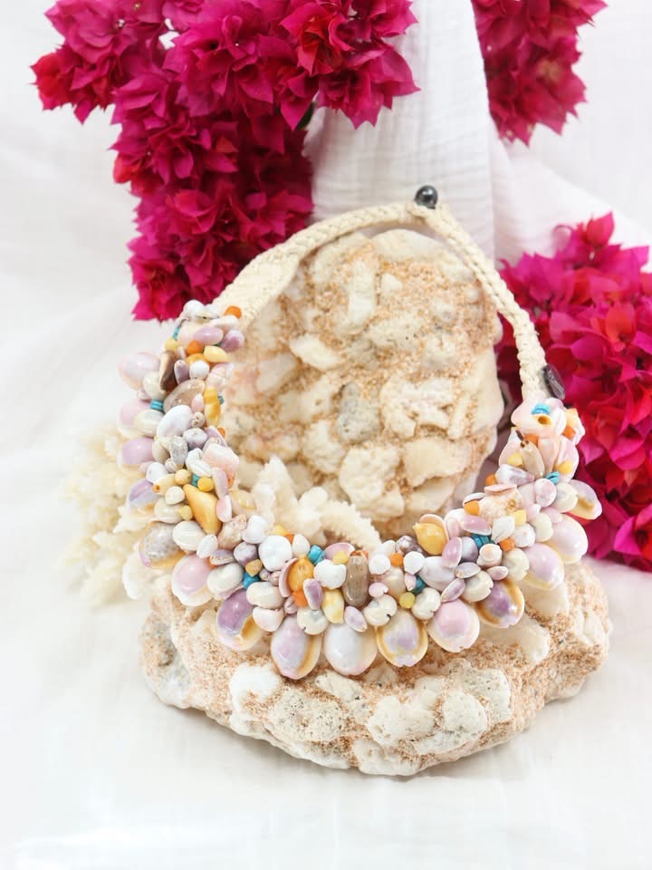 Collier artisanal en coquillages Manini Créations posé sur du corail, Tahiti